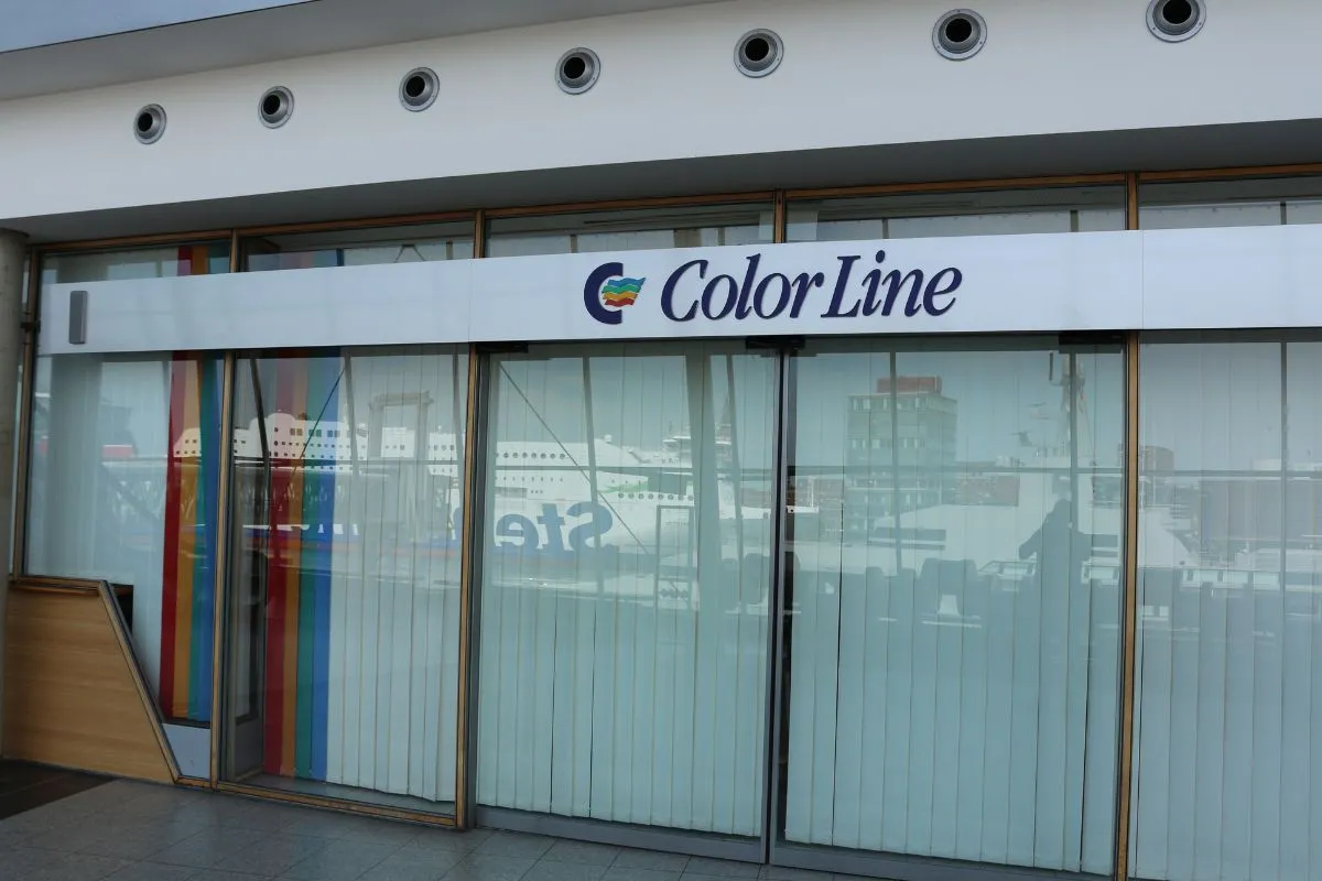Glasindgangen til en Color Line-færgeterminal, med et skib spejlet i dørene