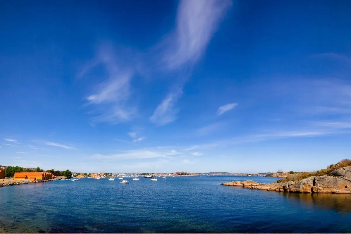The fjord at Larvik on a clear day, with moored sailing boats, low rocky shoreline and the town in the distance
